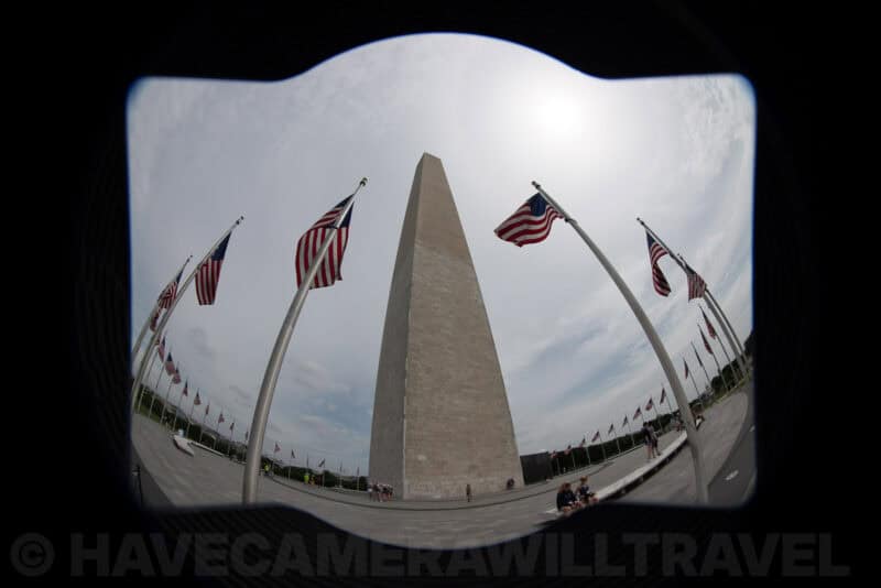 Fisheye lens hood vignette framing the Washington Monument surrounded by American flags
