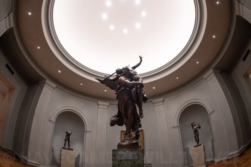 Bronze sculpture beneath a domed skylight in a museum gallery alcove