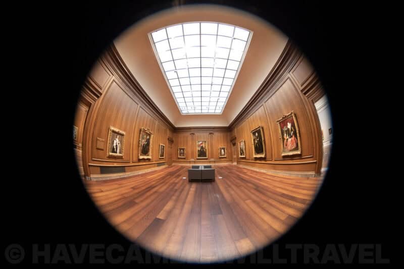 Wood-paneled gallery room with skylight and framed portraits at the National Gallery of Art