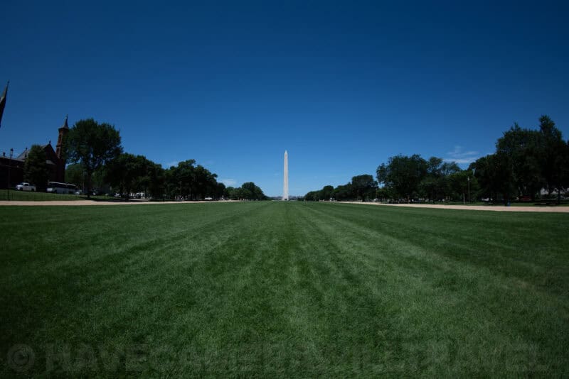 Washington Monument rising above a straight expanse of National Mall lawn under a clear blue sky