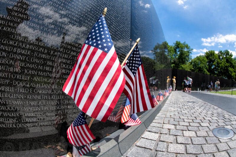 American flags reflected in the polished black granite of the Vietnam Veterans Memorial wall