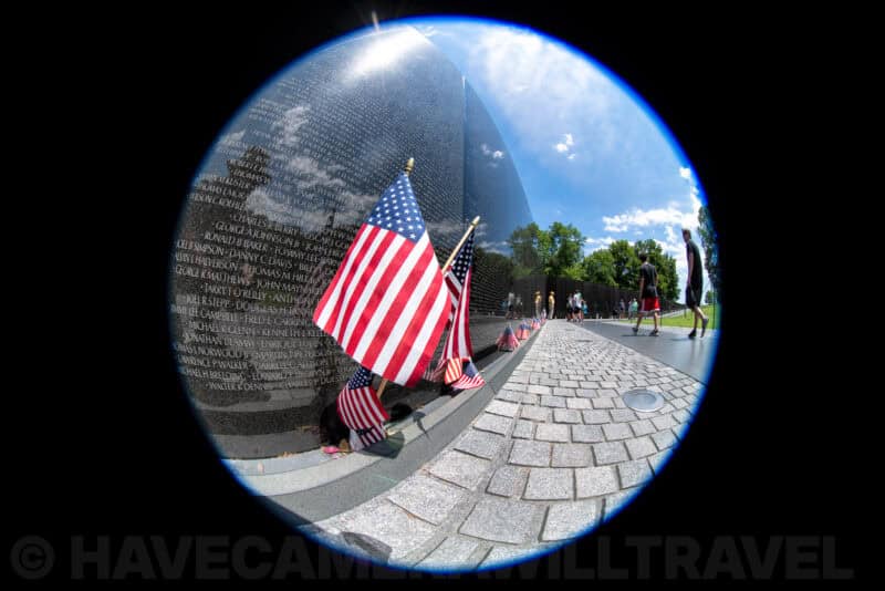 Circular fisheye view of American flags and names on the Vietnam Veterans Memorial wall