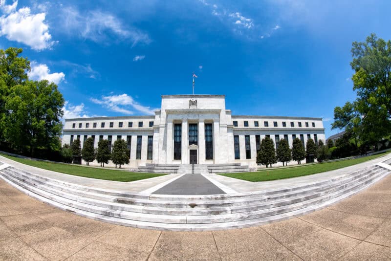 Federal Reserve building facade viewed from curved marble steps under a blue sky