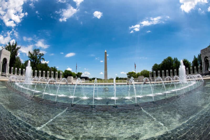 Fountain jets arcing at the National World War II Memorial with the Washington Monument in the background