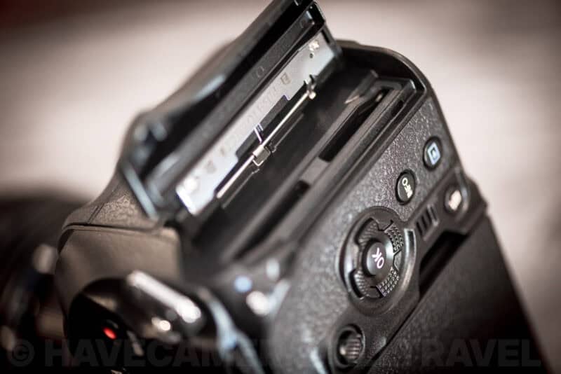 Open dual SD card slots on the OM-1 body with a memory card partly inserted
