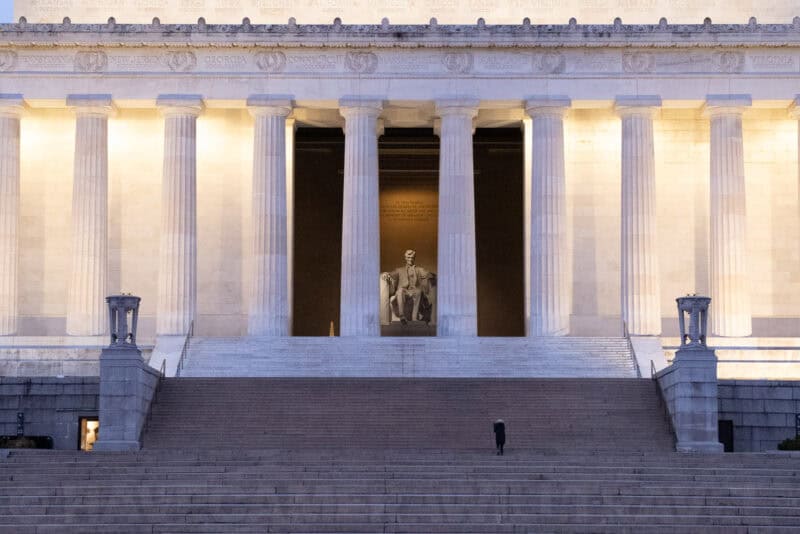 Lincoln Memorial facade at dusk with the illuminated statue of Lincoln visible between the columns