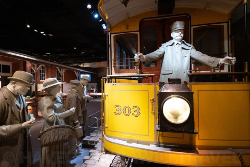 Antique yellow trolley car 303 and figures on a museum platform, ISO 10000 test shot