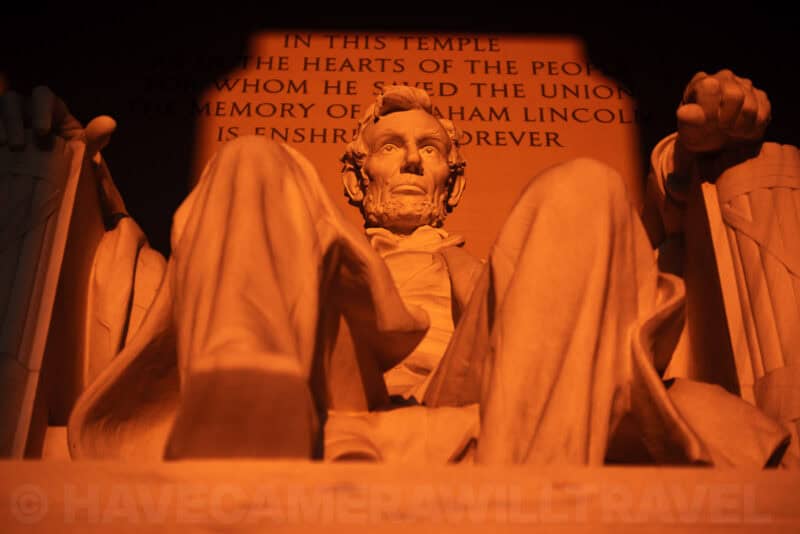 Lincoln Memorial statue glowing orange in the first light of sunrise with the engraved inscription behind