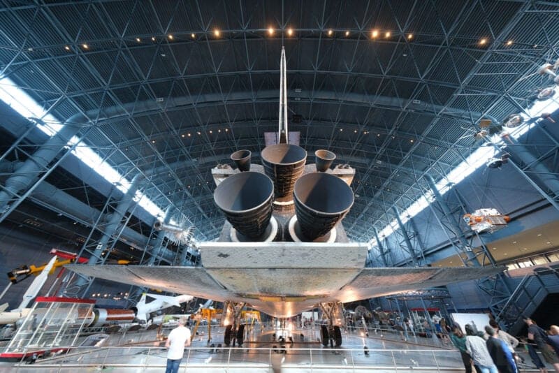 Rear underside of a space shuttle with visitors walking beneath it, ISO 400 sample image
