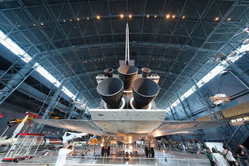 Museum visitors gather beneath a space shuttle's engine nozzles and fin, ISO 640 sample photo