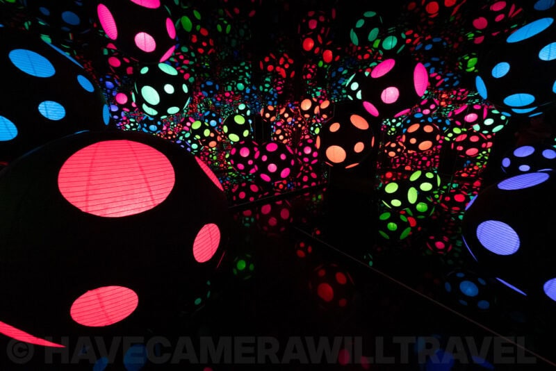 Kusama-style infinity mirror room filled with illuminated polka-dot orbs in neon colors