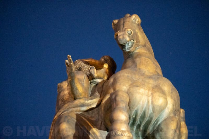 Close-up of a gilded equestrian statue's horse and rider against a dark blue night sky