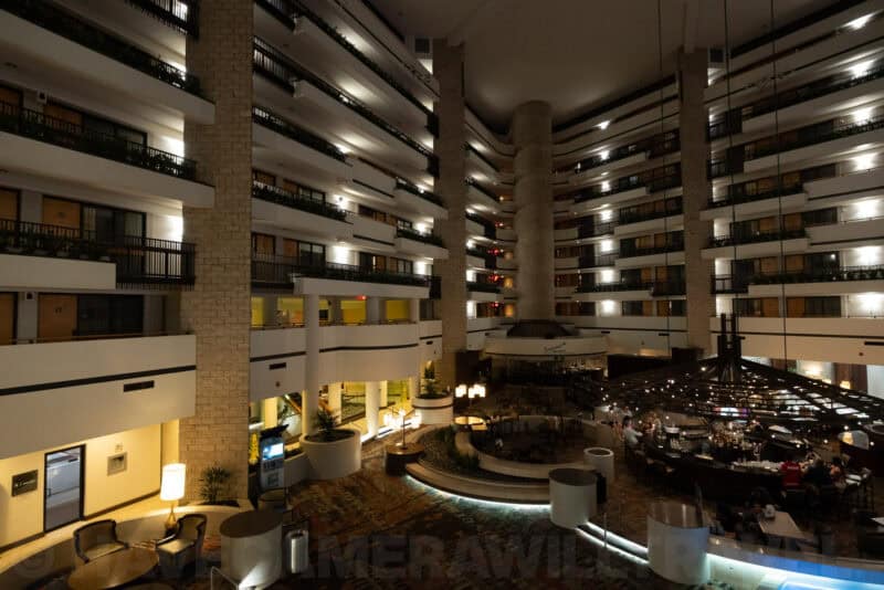 Multi-story hotel atrium with balconies overlooking a lobby and dining area at night