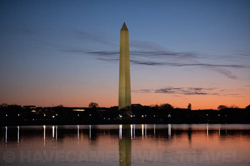 Washington Monument rising above the Tidal Basin with reflected shoreline lights at twilight