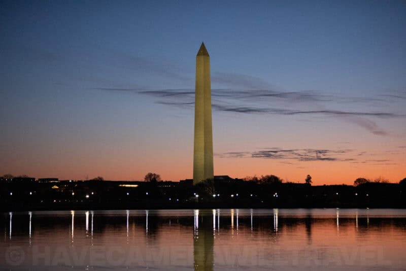 Washington Monument against a darkening sky with its reflection visible in calm water
