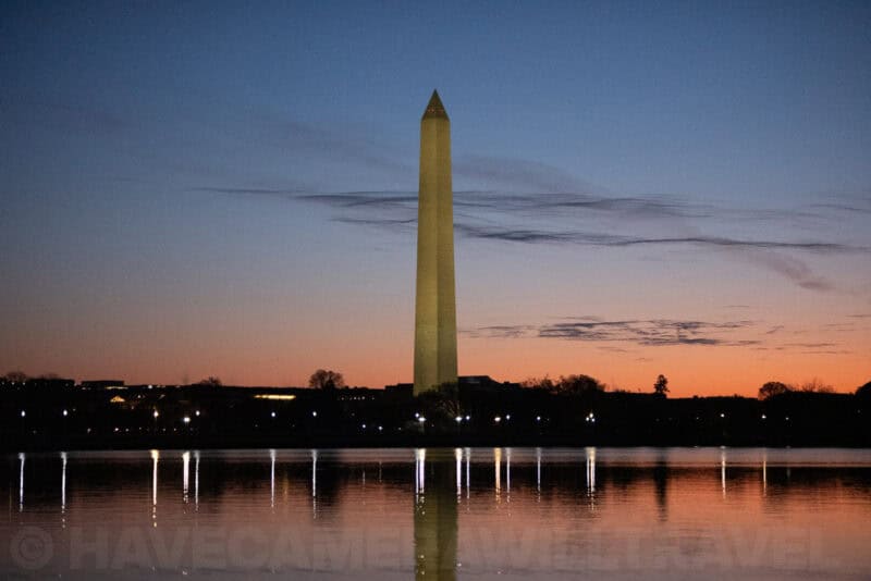 Washington Monument silhouette with orange horizon glow and rippled water reflections