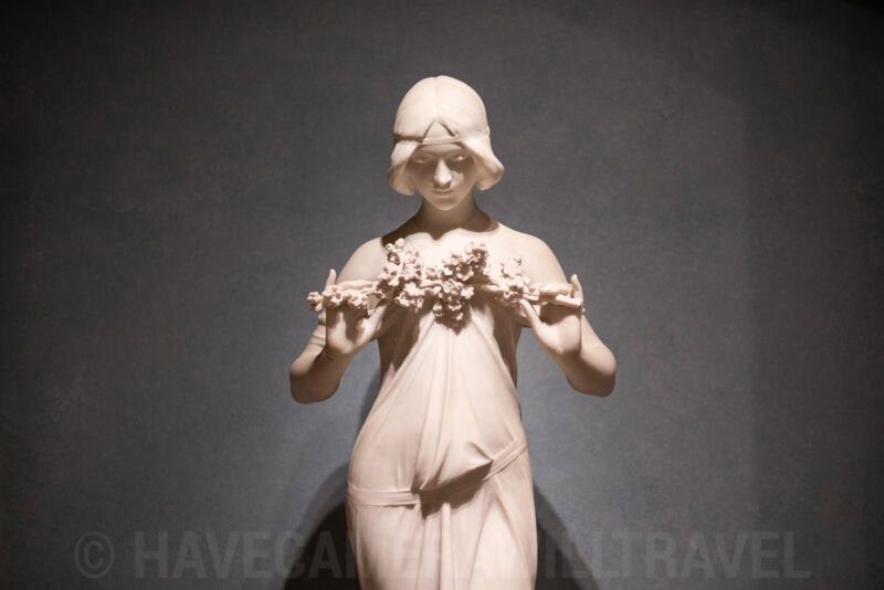 Classical marble statue of a woman holding a floral garland in a museum display