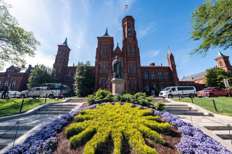 Smithsonian Castle red brick towers behind a colorful flower garden on a sunny day