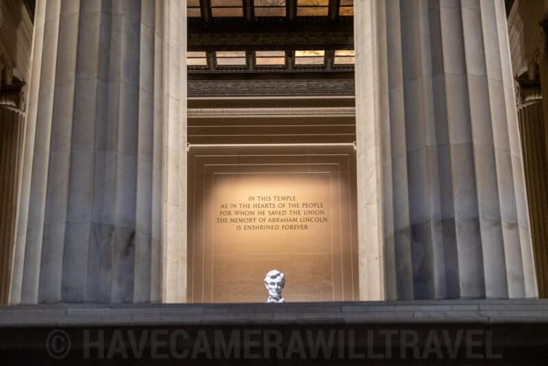 Lincoln Memorial columns framing the inscribed wall and small statue in the distance