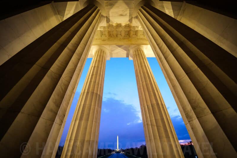 Washington Monument framed between the towering columns of the Lincoln Memorial at dusk