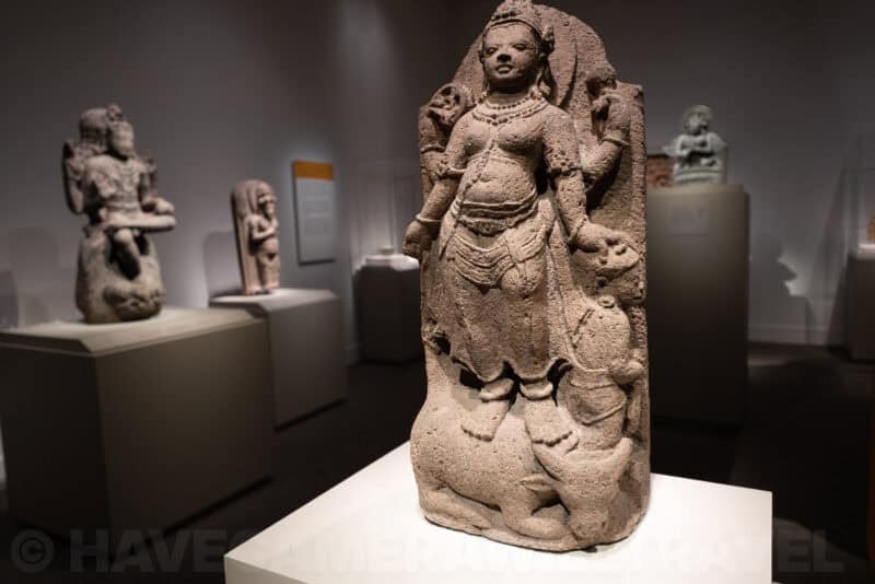 Carved stone sculpture of a Hindu deity displayed among other statues in a museum gallery