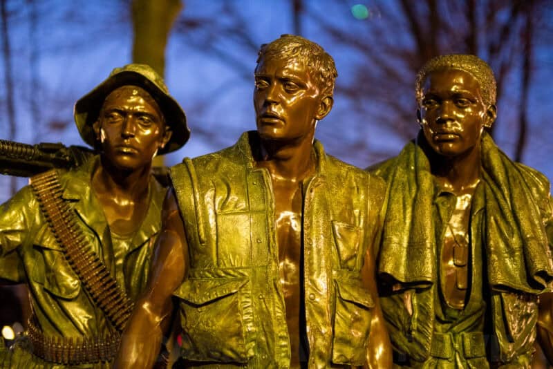 Close-up of the bronze Three Soldiers statue faces at the Vietnam Veterans Memorial at dusk