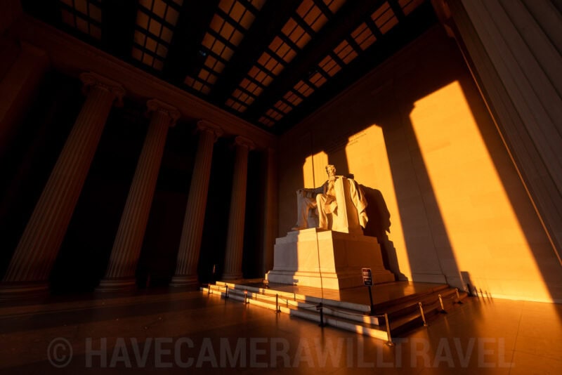 Lincoln Memorial statue glowing orange as sunrise light streams between its columns