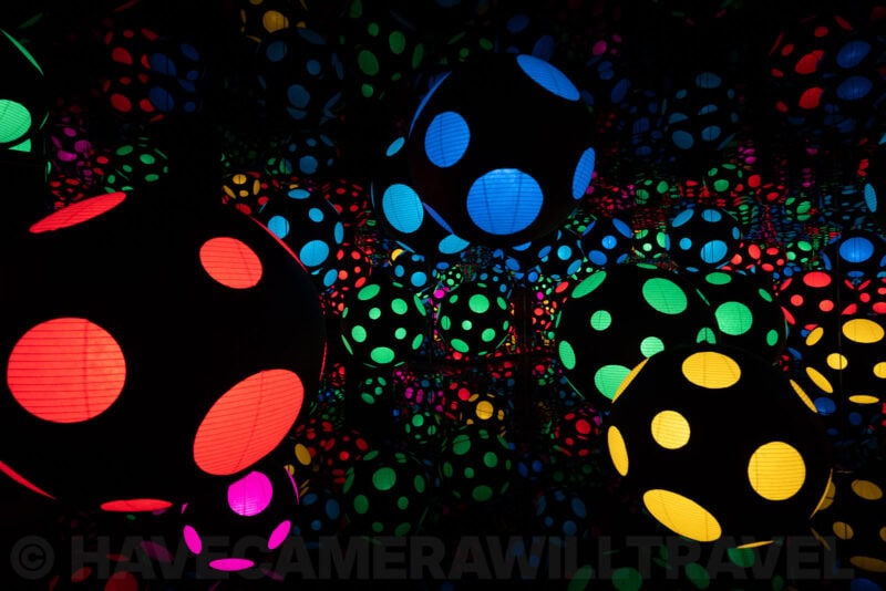 Immersive infinity room filled with glowing polka-dot spheres in red, blue, green, and yellow