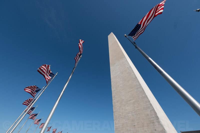 Washington Monument towering above rows of American flags, viewed from directly below