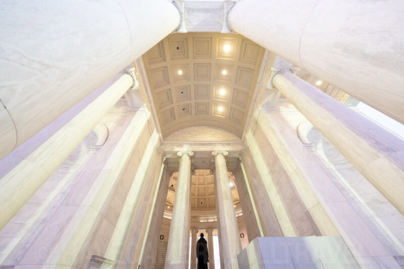 Jefferson Memorial interior columns and coffered ceiling with a silhouetted visitor below