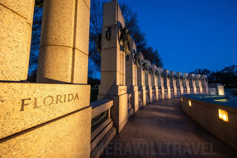 World War II Memorial pillars engraved with state names lit at dusk