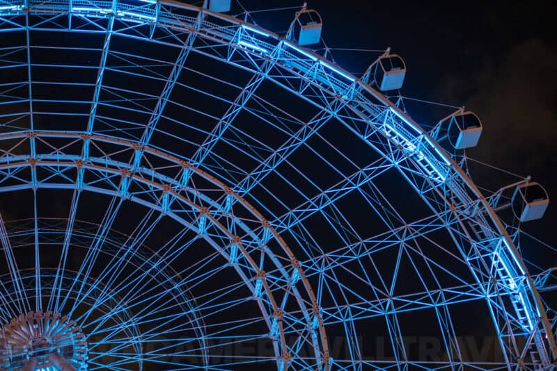 Illuminated blue Ferris wheel structure glowing against a dark night sky