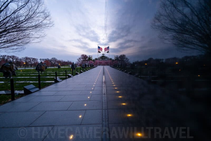 Vietnam Veterans Memorial reflecting pool walkway leading to flags, shot in monochrome at dusk