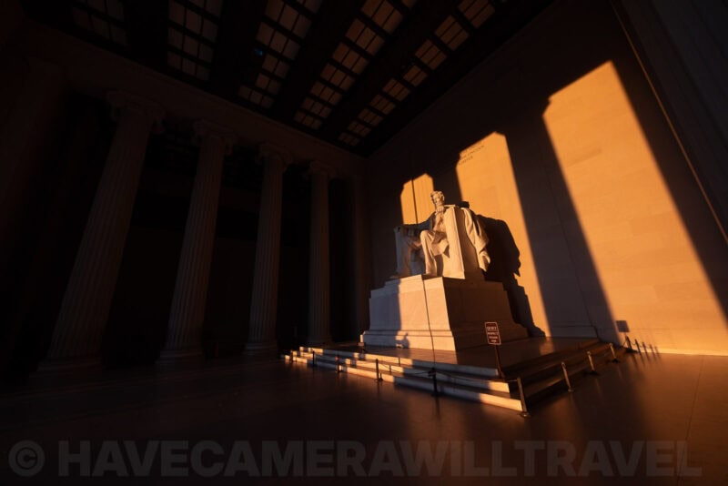 Lincoln Memorial statue lit by golden sunset light casting long shadows across the chamber