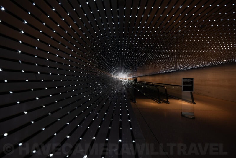 Illuminated tunnel walkway with rows of pinpoint lights converging in a hypnotic pattern