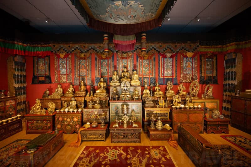 Tibetan Buddhist shrine room display filled with gilded statues and ornate painted furnishings