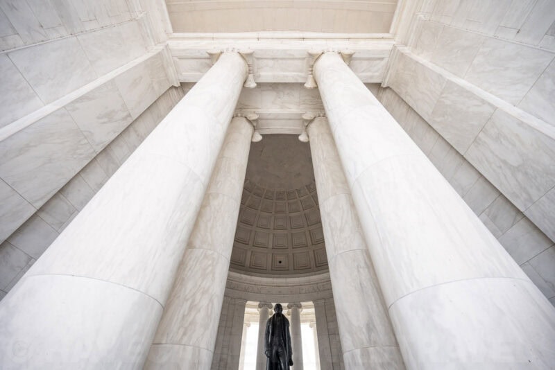 Tall marble columns rising toward the domed ceiling above the Jefferson statue at the Jefferson Memorial