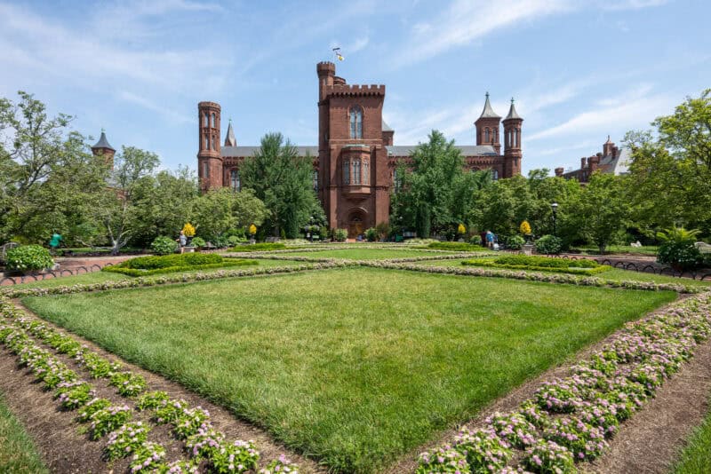 Smithsonian Castle's red sandstone towers viewed across a manicured formal garden lawn