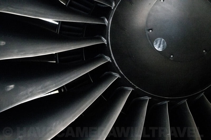 Close-up of a jet engine's turbine fan blades and metal hub in dramatic low light