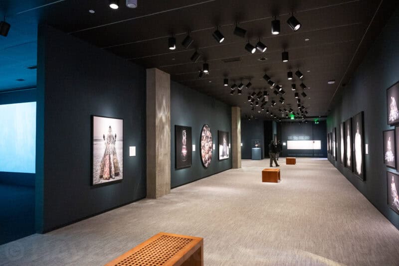 Long museum gallery corridor lined with framed photographs under angled spotlights