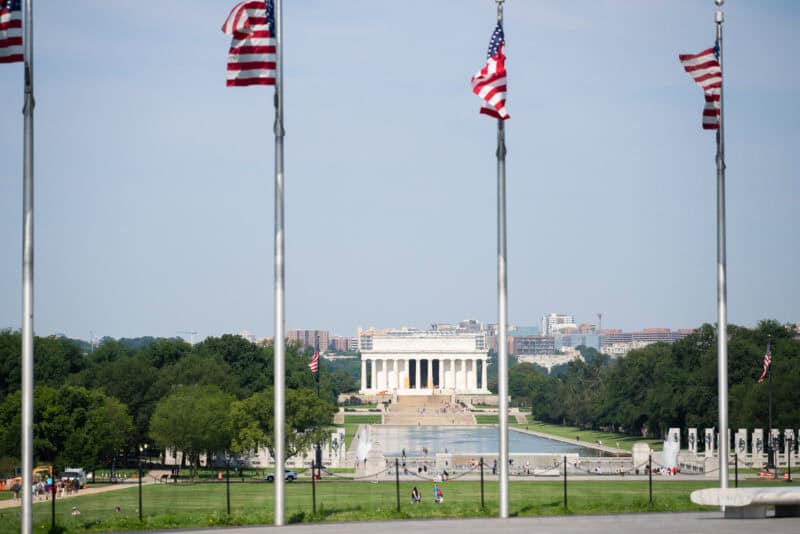 American flags framing a distant view of the Lincoln Memorial across the National Mall