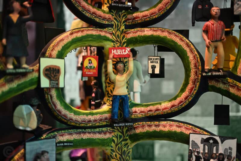 Carved folk-art tree of life figurine with a Dolores Huerta figure holding a Huelga sign, Nikon Zf ISO 5000 sample