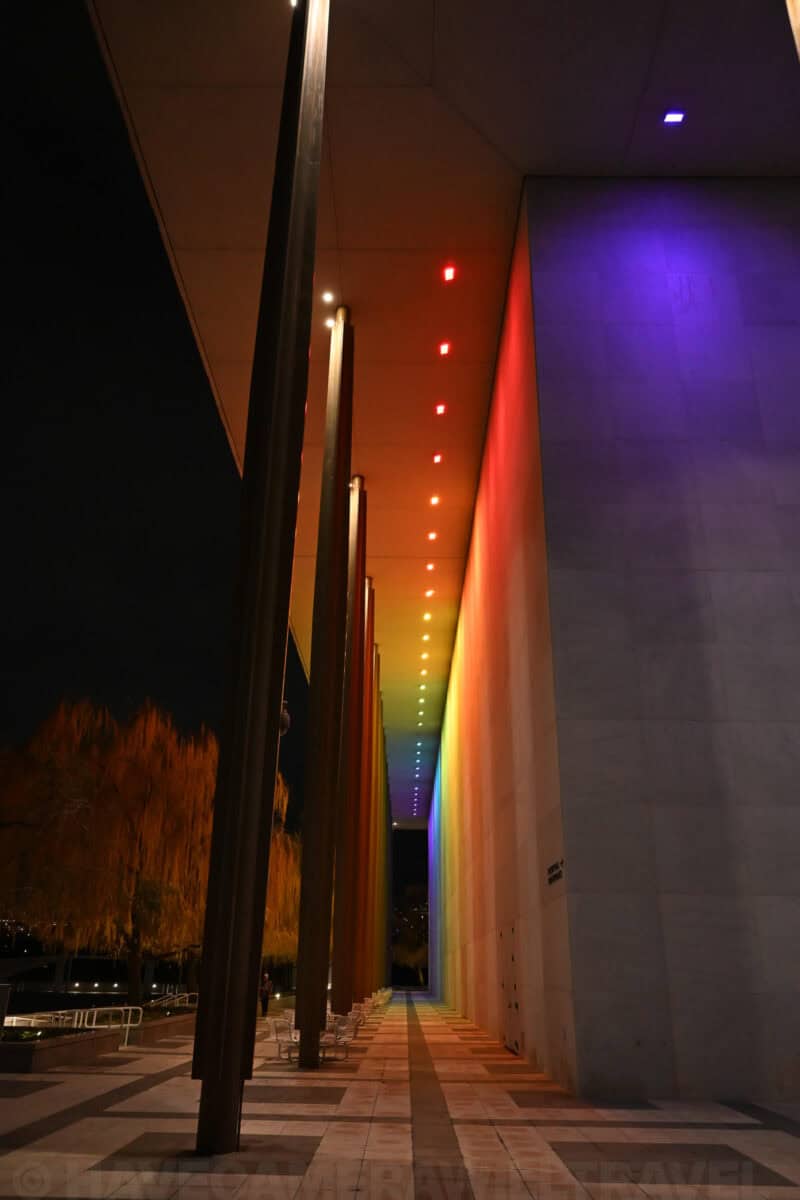 Rainbow-colored light installation along the Kennedy Center's outdoor colonnade at night