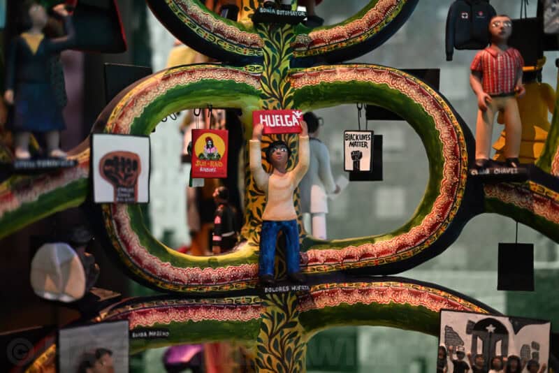 Close-up of a colorful tree of life folk sculpture with protest-themed miniature figures, Nikon Zf ISO 5000 sample
