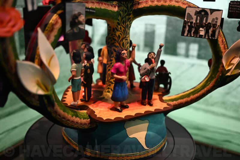 Wide view of an intricate tree of life sculpture with figures and protest signs, Nikon Zf ISO 8000 sample
