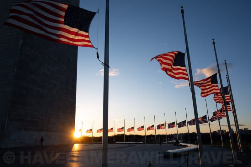 American flags at half-staff along the Washington Monument grounds at sunset