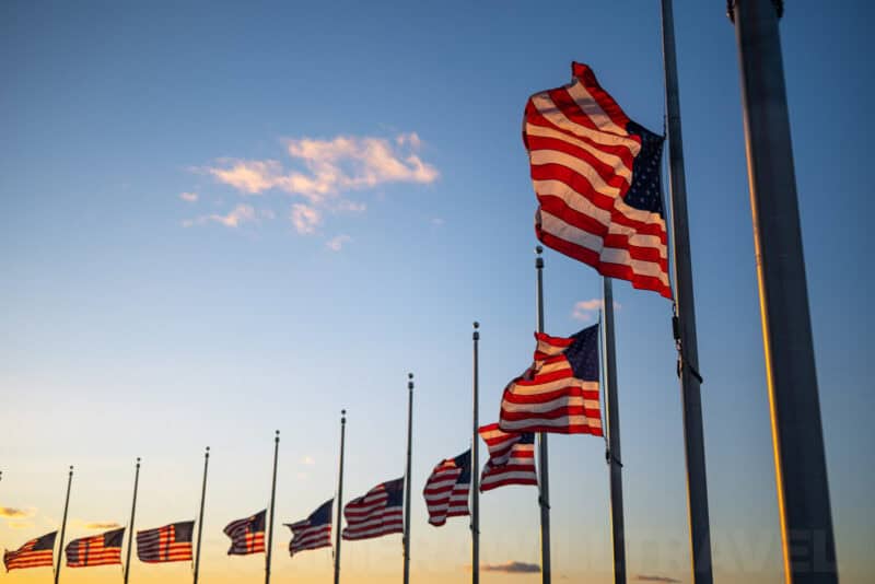 Row of American flags at half-staff flying at sunset near the Washington Monument grounds