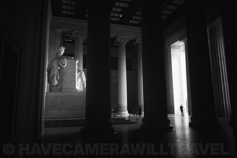 Lincoln Memorial statue seen between towering columns with light streaming through the entrance