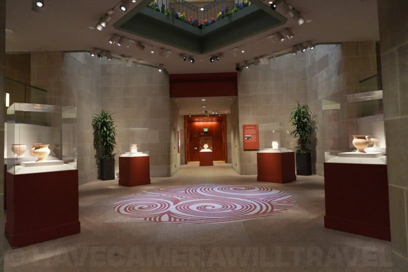 Museum gallery with pottery displays on red pedestals and spiral floor pattern, ISO 3200 sample