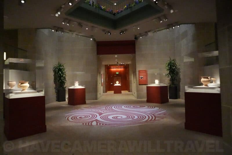 Museum gallery with vases on red pedestals and spiral rug pattern, ISO 20000 test shot